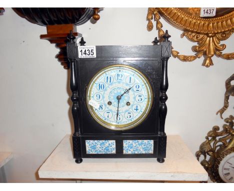 An ebonised mahogany mantel clock with blue and white porcelain face, side and front panels by Howell Jones
