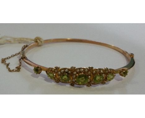 A Peridot and Seed Pearl Bangle, seven round claw set peridots ranging from 5.58 to 3.7mm, five of the peridots claw set in t