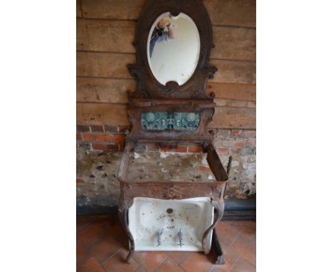 A Victorian cast iron console table with oval mirror above Art Nouveau style green ceramic tiles (lacks marble top), 186 cm h