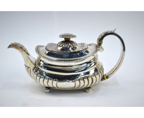 A Regency silver half-reeded teapot of squat oblong form with foliate applied handle and spout, ivory insulators and ball fee