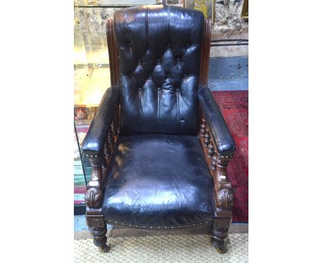 A Victorian mahogany framed black button leather backed library armchair, the overstuffed arms over turned spindles and raise