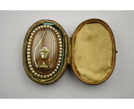 A Georgian oval mourning brooch featuring a mother of pearl urn beneath seed pearl set weeping willow upon light brown hair b