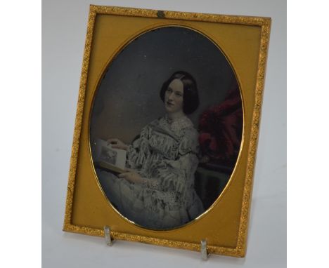 An elegant coloured ambrotype, or other process, of a young women reading a book, mounted in gilt metal, overall dimensions a