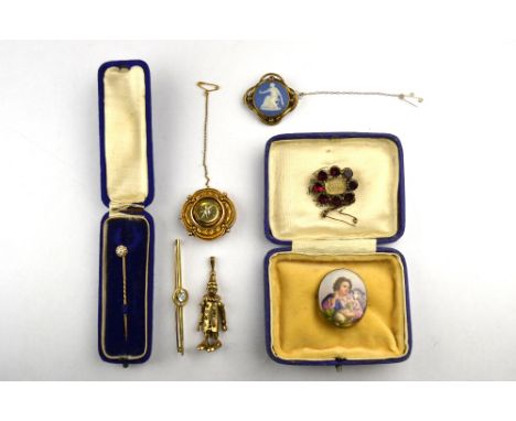 A collection of four antique brooches including allegorical porcelain scene of female with lambs, garnet set mourning brooch 