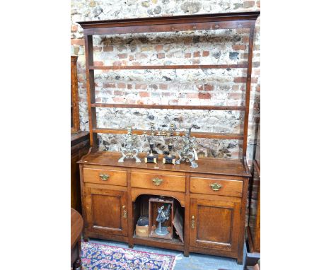 A George III oak high dresser, the open three tier rack over three frieze drawers and an open shelf flanked by panelled cupbo