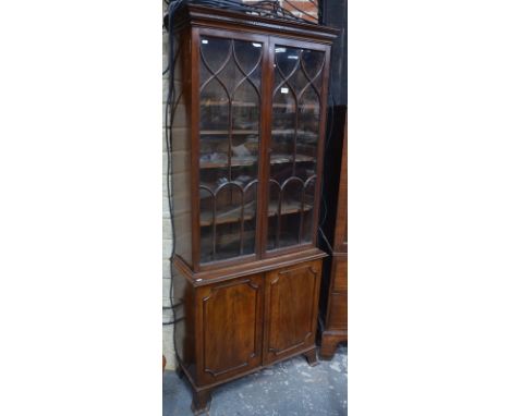 A mahogany cabinet bookcase of small proportions with moulded cornice above twin glazed doors and lower panelled doors, on br