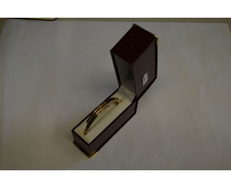 A yellow and white metal hinged bangle stamped 375, approx 9.4 g