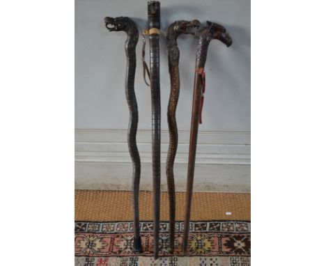 Three carved wood walking sticks with dragon's head handles and another stick carved as a cobra (4)