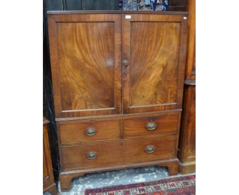 A George III  mahogany low linen press with twin panelled doors enclosing sliding shelves, two short drawers and one long dra