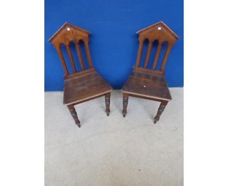A pair of Edwardian walnut hall chairs with architectural back rests. 