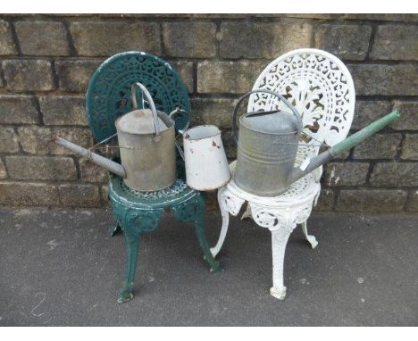 Two metal garden chairs, two galvanised watering cans and an enamel jug. 