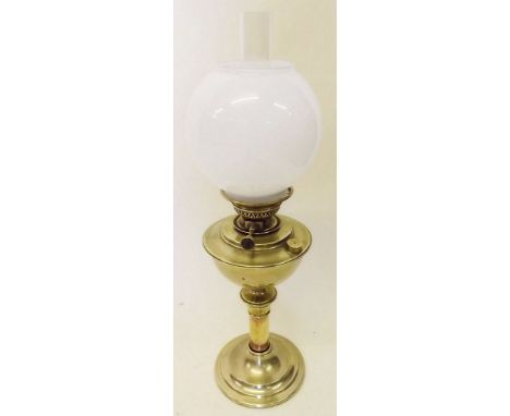 A brass oil lamp with opaque glass shade