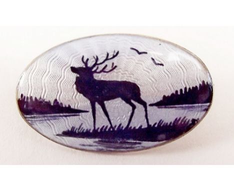 A silver and enamel brooch by Nils Elvik depicting stag by a lake, marked NE in horseshoe