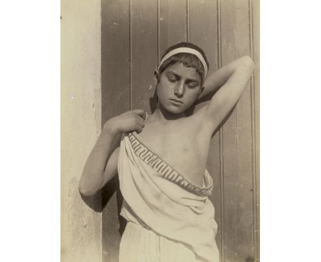 Gloeden, Wilhelm von -- Young boy in toga with headband. 1890s. Albumen print. 21,7 x 16,5 cm. Photographer's stamp and numbe