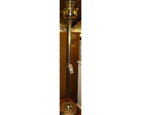 An early 20th century polished brass paraffin lamp, having a floral milk glass shade, height 150cm