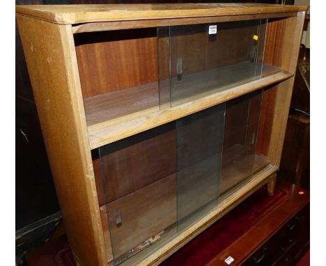 A 1970s light oak low bookcase with four glazed sliding doors, width 92cm