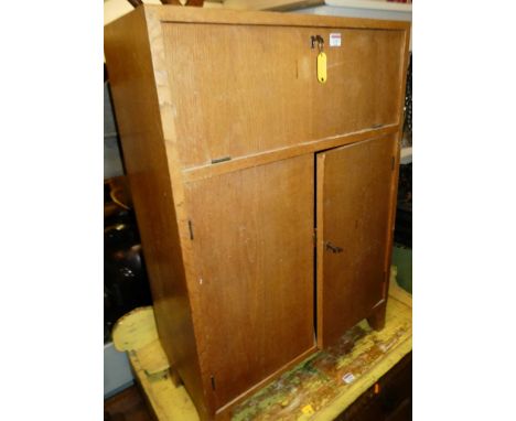 A 1970s light oak student's bureau, with fall front compartment over twin lower cupboard doors, width 64.5cm