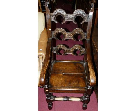 A joined oak panelled seat elbow chair, having chip carved horseshoe shaped ladder back, raised on turned and square cut supp