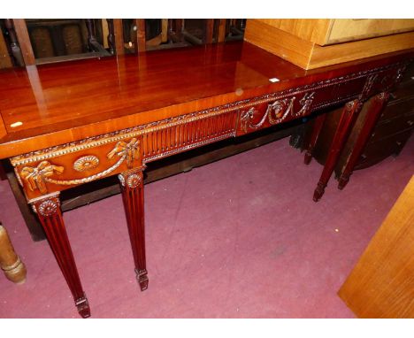 A contemporary mahogany long console table, in the Adam style, having swag and bow decoration with central rams head, on flut