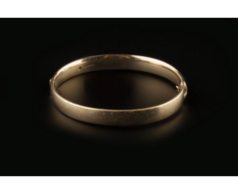 A 9CT GOLD BANGLE, of hinged oval form, with Millennium hallmark, inner diameter 6.3cm