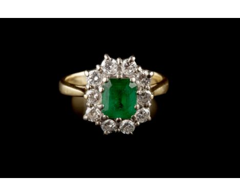 AN EMERALD AND DIAMOND CLUSTER RING, the rectangular step-cut emerald claw set within a border of round brilliant-cut diamond