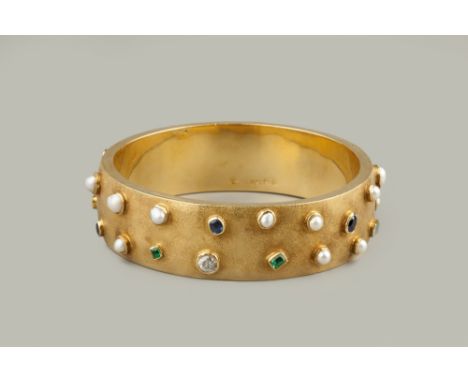 A DIAMOND, HALF PEARL AND VARI GEM-SET BANGLE,  circa 1940, of wide continuous form, applied with collet set gemstones of gra
