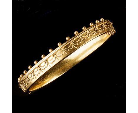 A VICTORIAN BANGLE, of hinged oval form, applied to the front with a frieze of scalloped ropetwist wirework, to a bead border