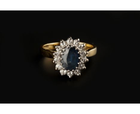 A SAPPHIRE AND DIAMOND CLUSTER RING, the oval mixed-cut sapphire claw set within a border of round brilliant-cut diamonds, 18