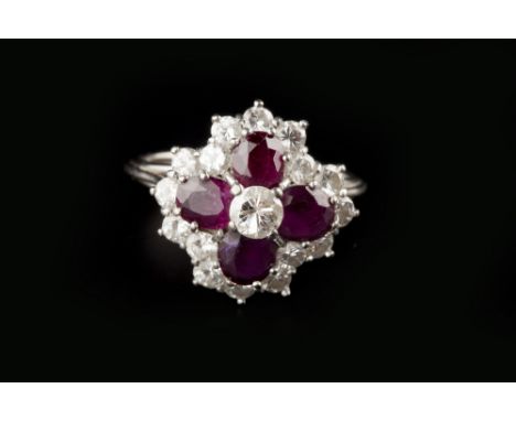 A RUBY AND DIAMOND CLUSTER RING, the principal round brilliant-cut diamond framed by four oval mixed-cut rubies, within an ou