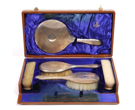 A SILVER BACKED DRESSING TABLE SET, with engine turned decoration and comprising hand mirror, two hairbrushes and two clothes