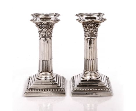 A PAIR OF VICTORIAN SILVER CANDLESTICKS, of corinthian column designs having beaded drip pans and stepped square bases by Edw