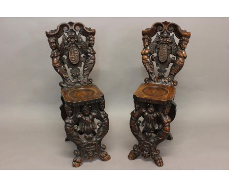 A NEAR PAIR OF VENETIAN STYLE SCABELLO HALL CHAIRS. Each with elaborate scrolling backs with a grotesque head above a coat of