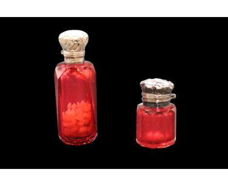 Two Victorian silver-mounted ruby glass smelling salts / scent bottles, each having a ground-in stopper and hinged cap, talle