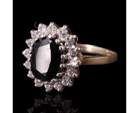 A sapphire ring, the oval cut gemstone of approx 1.5 cts, claw-set above a ring of white stones on a 9 ct gold shank, K/L, 2.