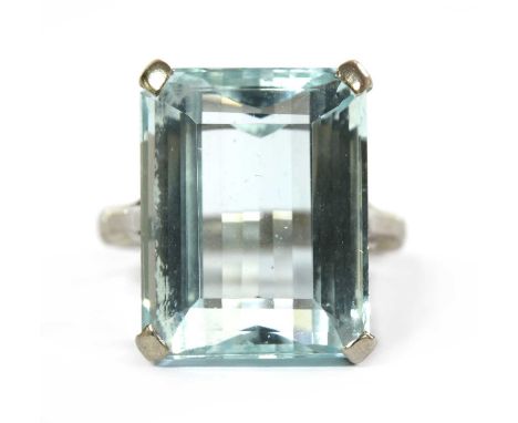 A white gold single stone aquamarine ring, with a step cut aquamarine, 17.4 x 13.7 x 9.1mm, claw set, to trifurcated shoulder