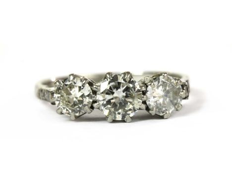 A three stone diamond ring, with a row of graduated brilliant cut diamonds, claw set to rex collets, to chenier shoulders gra