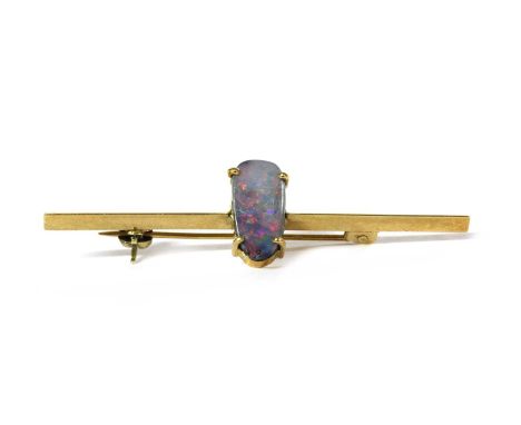 A gold boulder opal bar brooch, with an oval boulder opal, approximately 10.4 x 5.2mm, claw set, to a triangular section gold