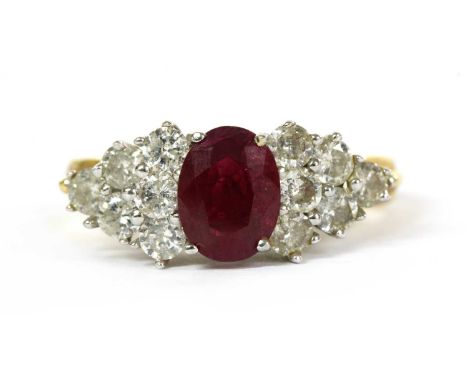 An 18ct gold ruby and diamond ring, with an oval mixed cut ruby, possibly fracture filled, with a cluster of brilliant cut di