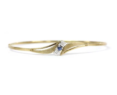 A 9ct gold sapphire and diamond bangle, with a round mixed cut sapphire and two eight cut diamonds claw set on the diagonal, 