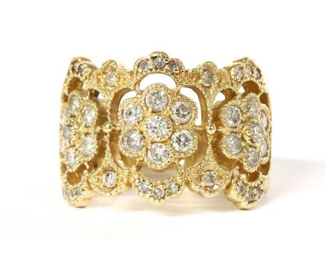 A gold diamond ring, with three daisy clusters milligrain set with brilliant cut diamonds, to an openwork scalloped frame mil
