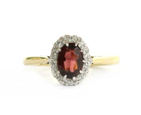 A gold garnet and diamond cluster ring, with an oval mixed cut garnet to surround of eight cut diamonds, with tapered chenier