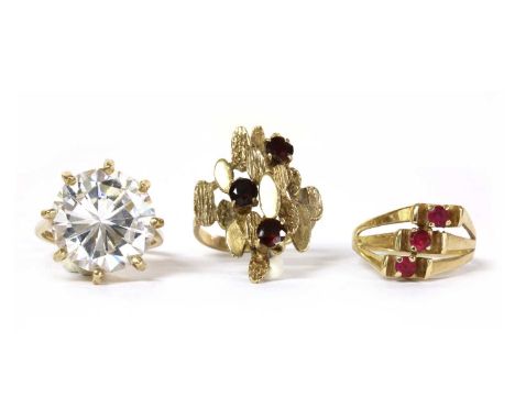 Three gold rings, to include a 9ct gold garnet ring, c.1970, the head with polished and textured plates, claw set with scatte