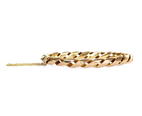 A gold hinged oval bangle, with two rows of wire twisted as a double helix, to concealed box clasp and safety chain, tested a