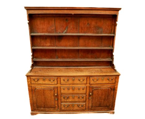 A late 18th Century / early 19th Century oak Dresser, the top with moulded cornice above graduating fitted shelves, shaped si