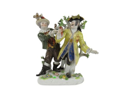 A large Meissen Group,&nbsp;with gentleman in bright yellow coat, and a Jester in green coat, offering a mouse in a trap, jes