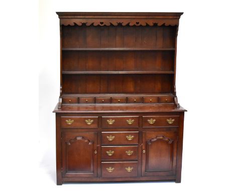 A reproduction oak dresser with plate rack back, with an assortment of seven spice drawers, six further drawers and two panel