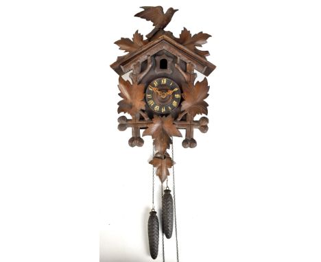 A circa 1900 Black Forest carved stained beech cuckoo clock featuring leaf and bird decoration with twin pine cone weights, h