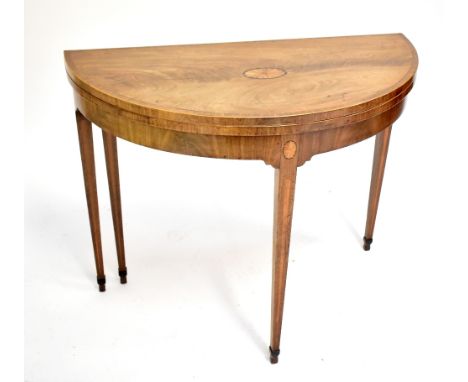 A George III mahogany crossbanded boxwood strung and satinwood inlaid demi-lune card table, raised on square sectioned taperi