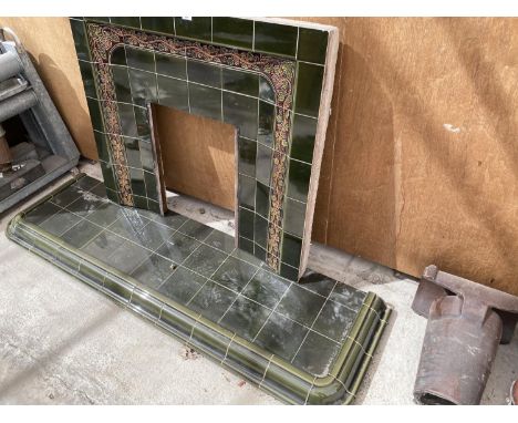 A GREEN TILED FIREPLACE SURROUND AND HEARTHWITH ORNATE GRAPEVINE DESIGN 