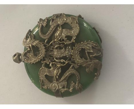 A GREEN STONE PENDANT WITH WHITE METAL DRAGON DECORATION (POSSIBLY JADE) 